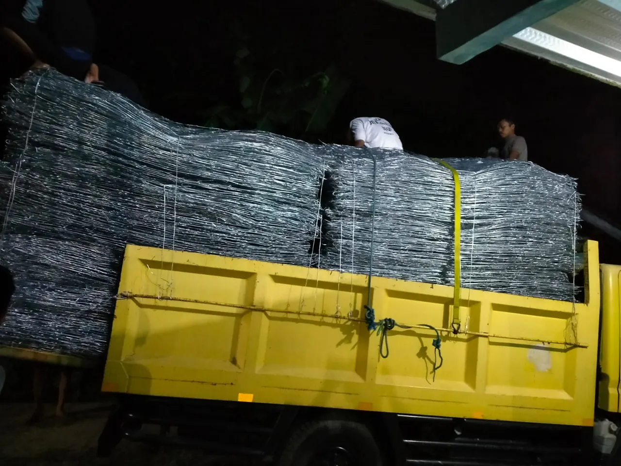 Truk kuning bermuatan tumpukan bronjong kawat galvanis