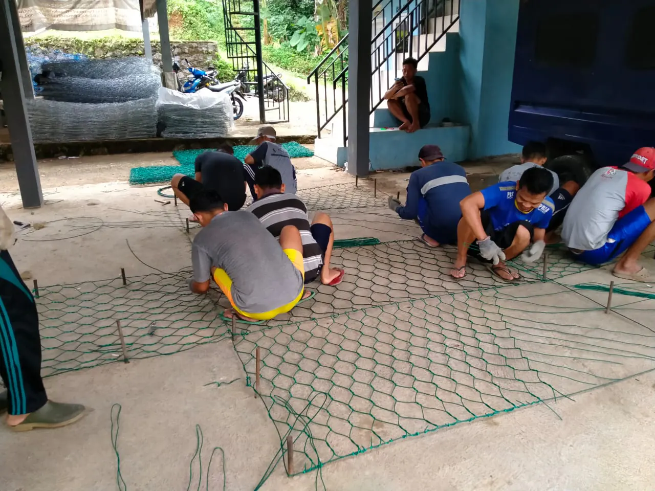 Pekerja menganyam bronjong kawat PVC hijau di area produksi