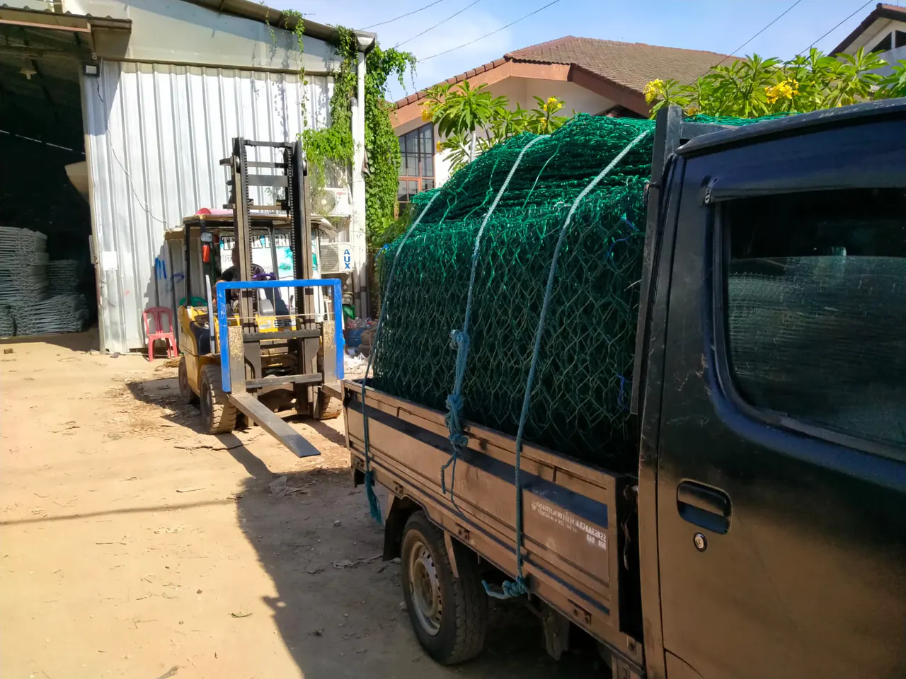Bronjong kawat PVC hijau di bak pick-up dengan forklift di area gudang
