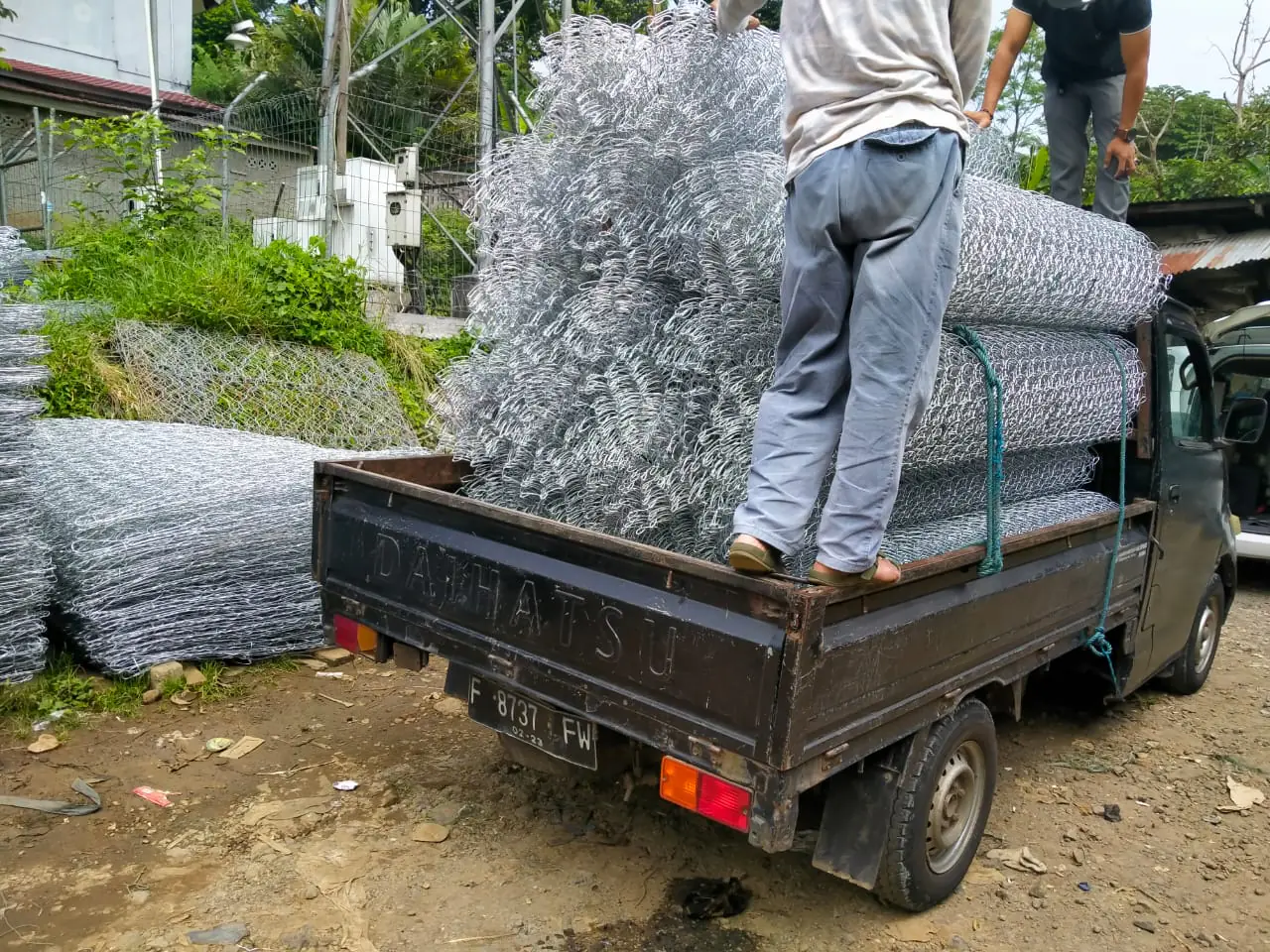 Pekerja menaikkan gulungan kawat galvanis ke bak truk