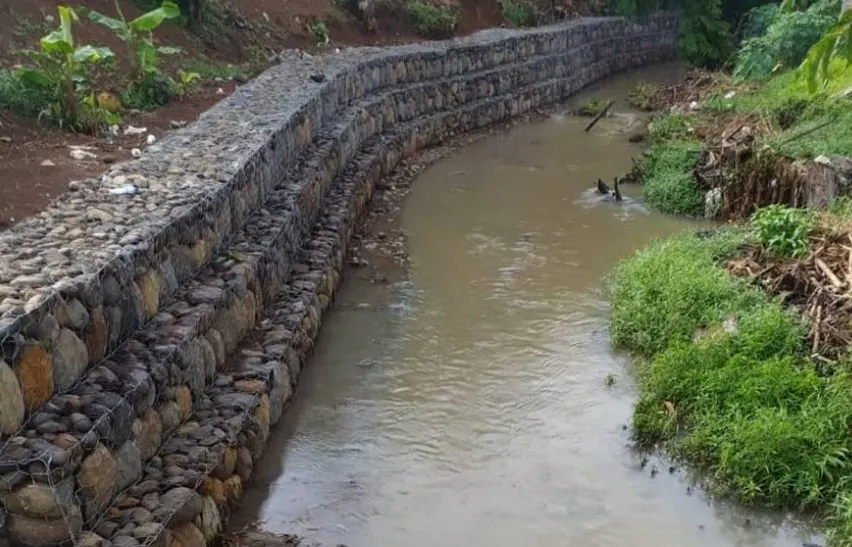 Dinding bronjong batu melengkung di tepi sungai